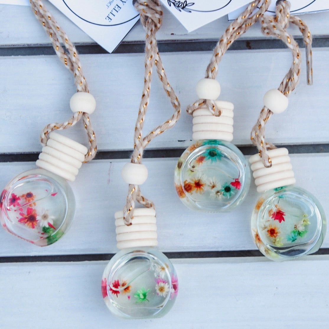 Decorative light bulbs with floral designs hanging on a white surface.