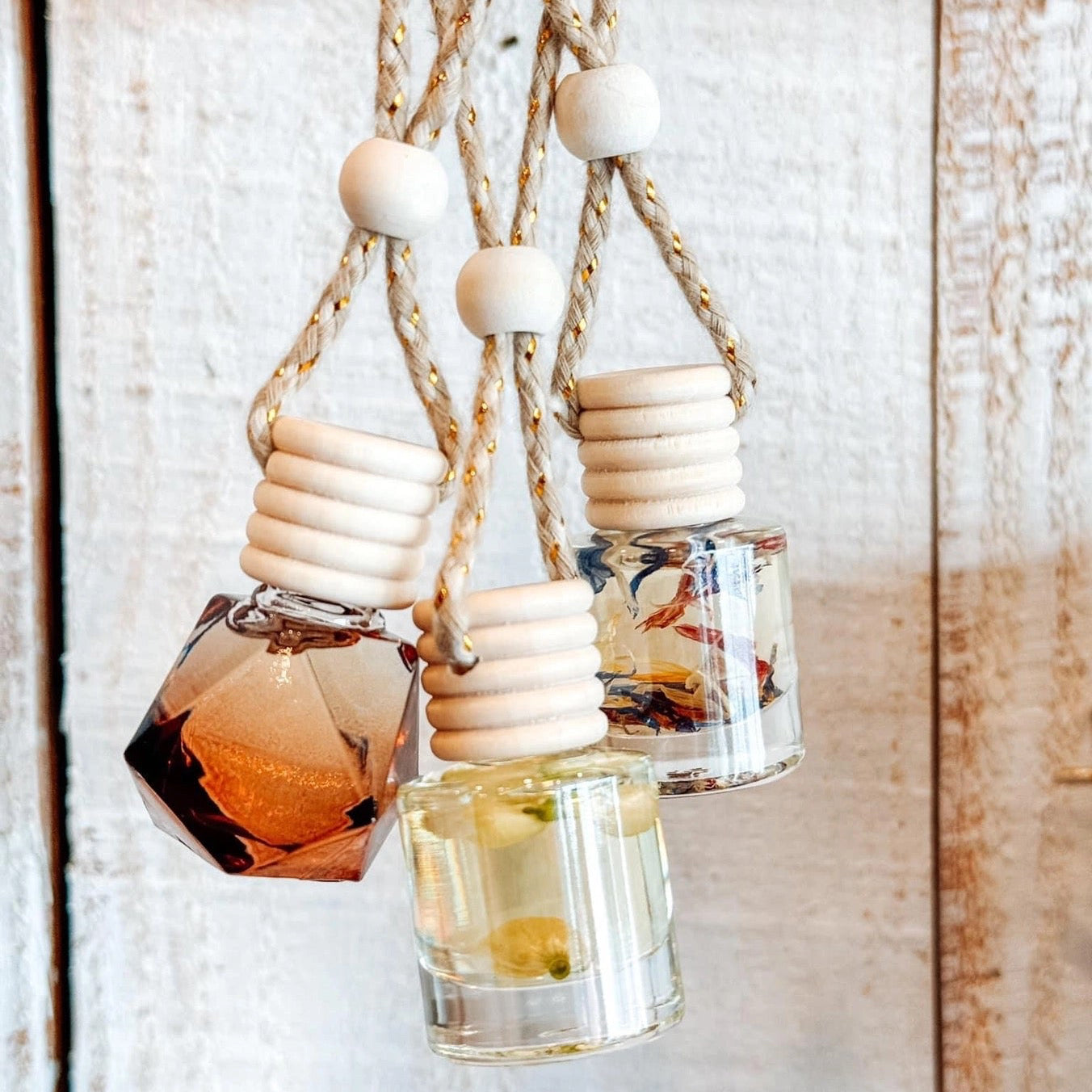 Three small glass bottles with wooden caps hanging from a rope on a wooden background