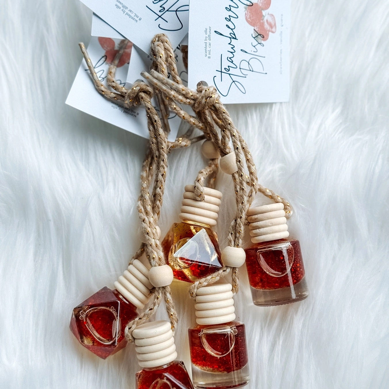 Set of small bottles with wooden caps on a white fluffy surface, with 'Strawberry Bliss' card in the background.