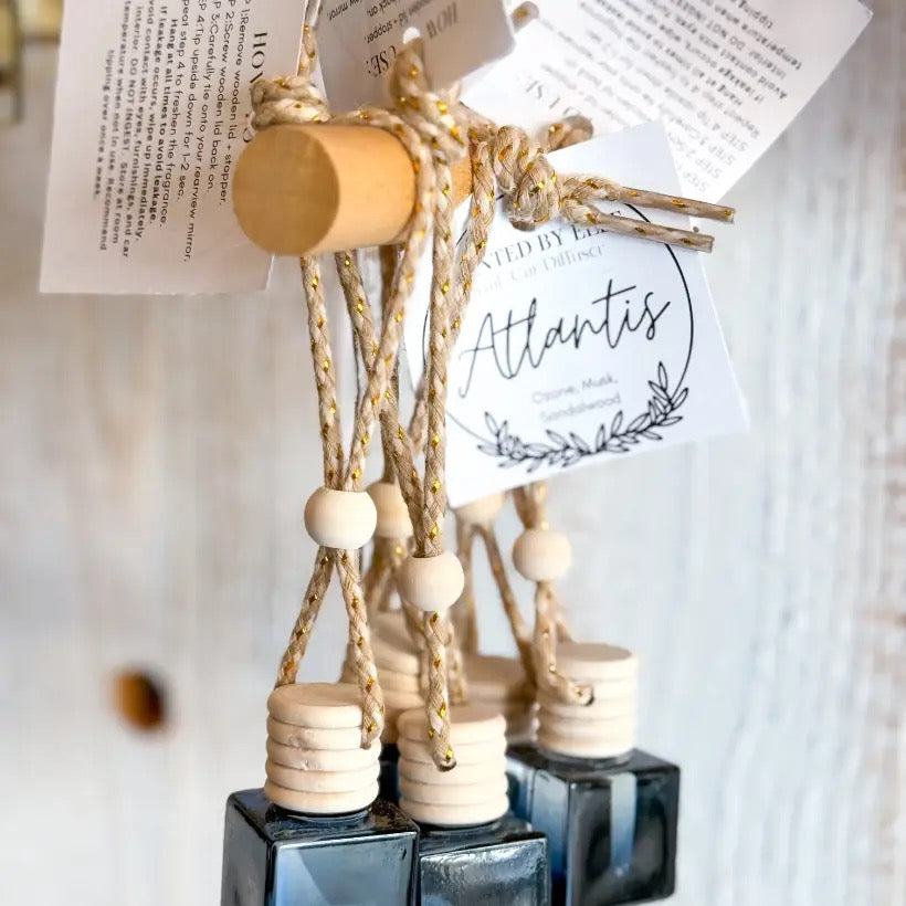 Black Atlantis bottles with wooden caps and hanging product tags displayed on a wooden peg rack.