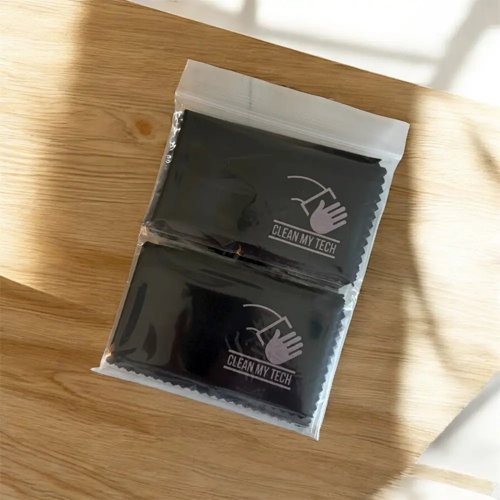 Two black microfiber cleaning cloths, each sealed in a clear plastic bag with ’clean my tech’ branding and an illustrated hand icon.
