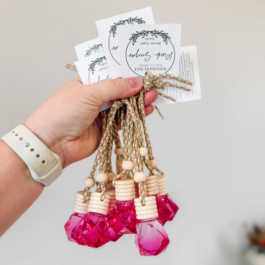 Hand holding pink beaded bottle with tags on a light background