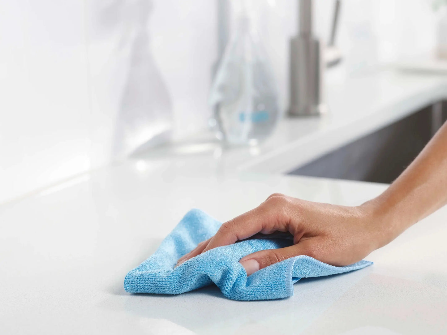 A soft, light blue microfiber cloth being used to wipe a countertop.
