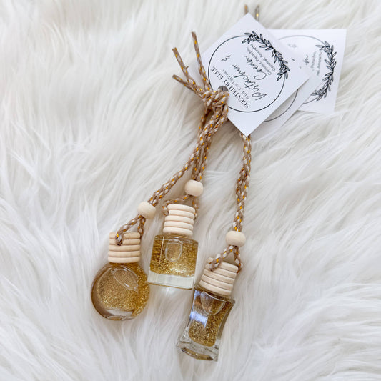 Small glass bottles with gold glitter on a white fluffy surface