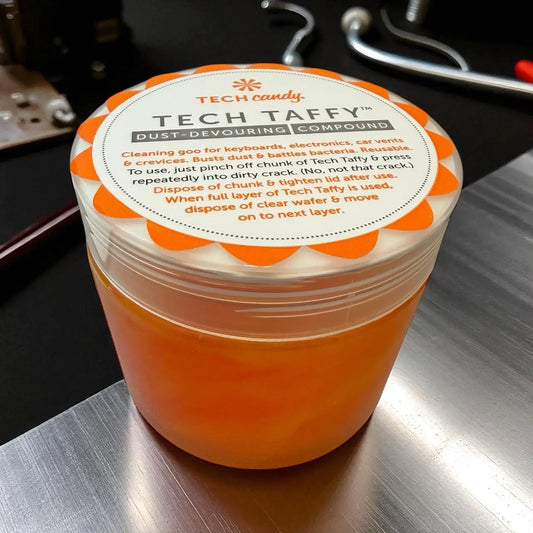 Orange tech candy tech taffy dust-devouring compound in a clear plastic jar with an orange and white scalloped lid.