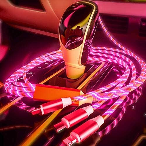 Gold car charger with pink and red cables on a car dashboard