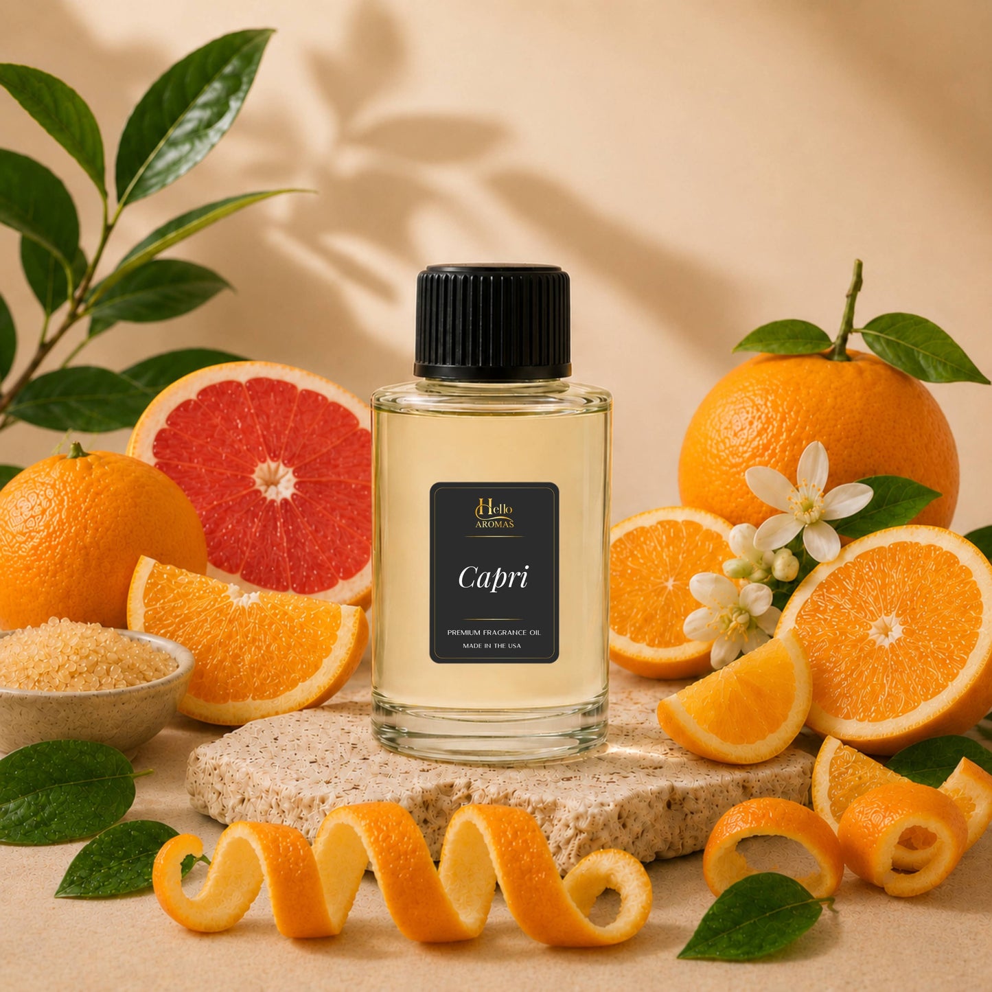 A clear glass bottle with a black cap and a black label reading 'Capri' stands centered on a stone slab, surrounded by citrus fruits, grapefruit slices, orange peels, leaves, and small white flowers against a warm beige background.