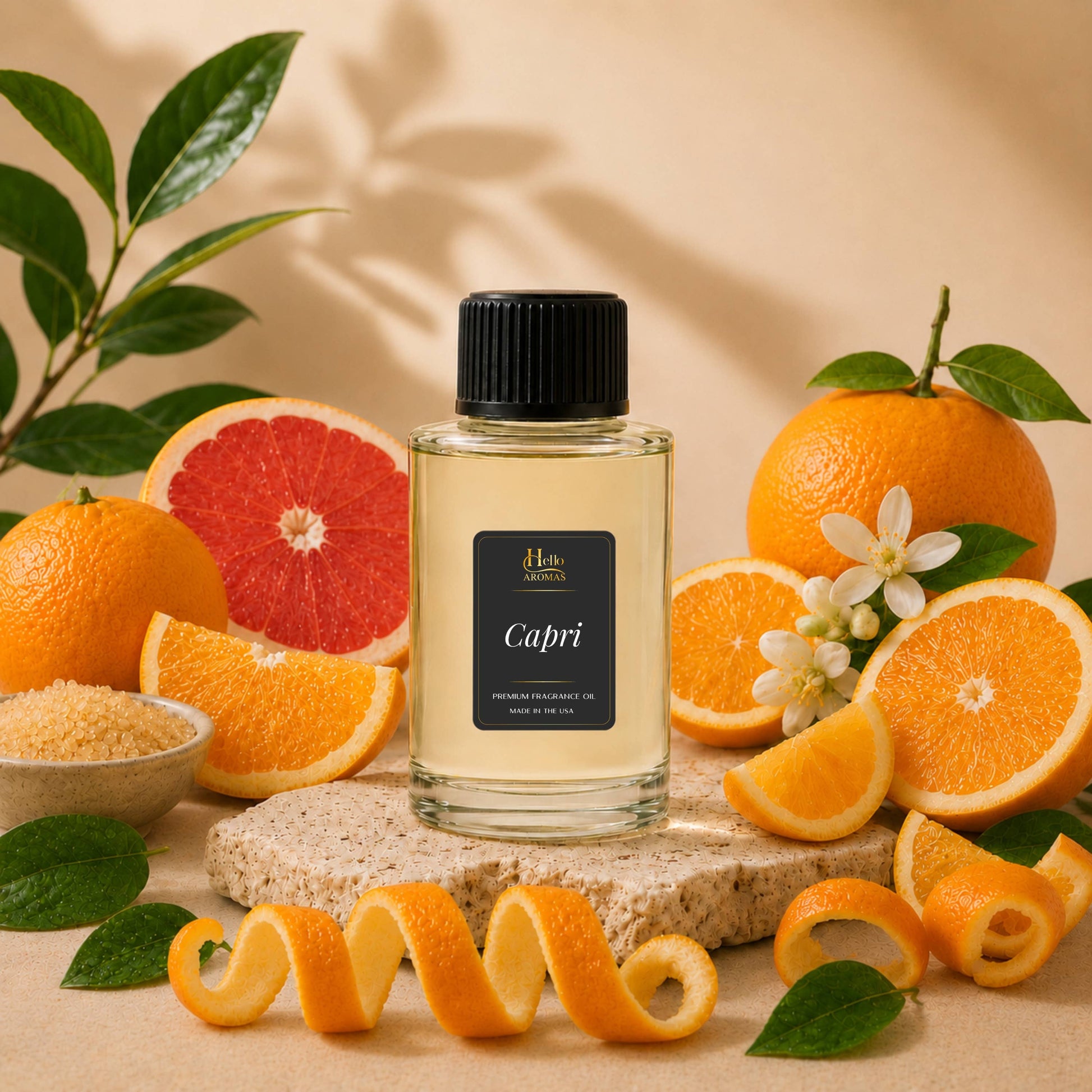 A clear glass bottle with a black cap and a black label reading 'Capri' stands centered on a stone slab, surrounded by citrus fruits, grapefruit slices, orange peels, leaves, and small white flowers against a warm beige background.