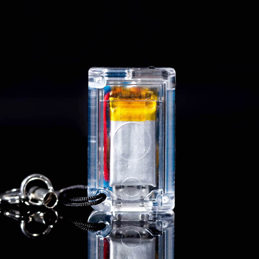 The back of the clear tiny game console on a black background with a keychain attached. 