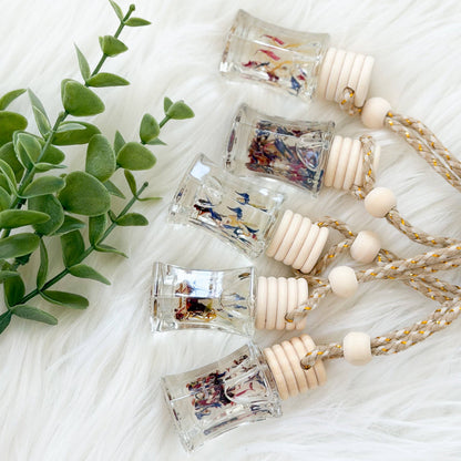 Set of small glass bottles with decorative labels on a white surface with a plant in the corner.