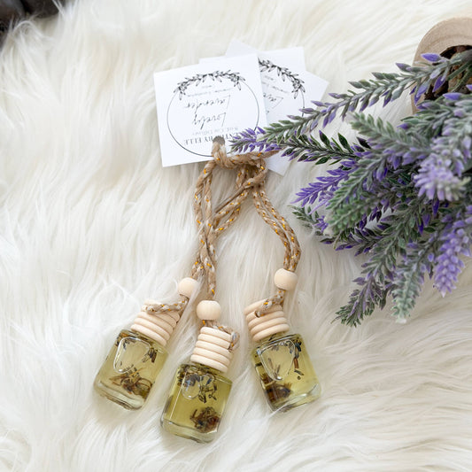 Three small glass bottles with natural elements on a fluffy white surface with lavender flowers.