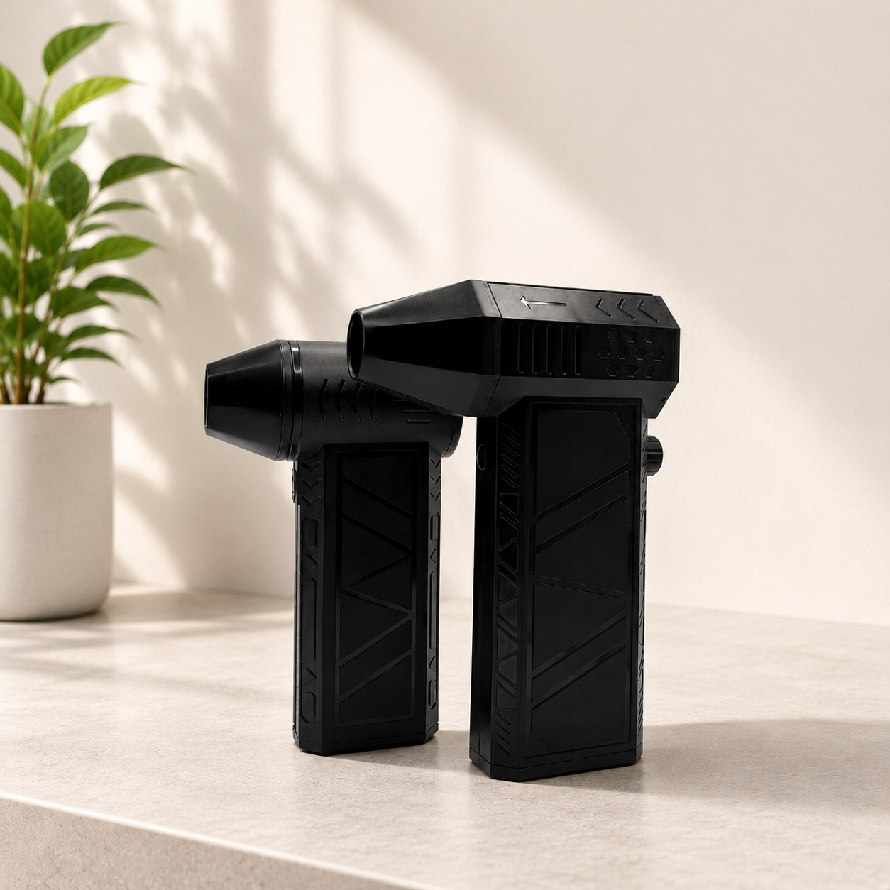 2 different size black air dusters on a counter with plant in the background 