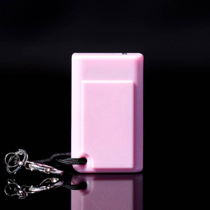 The back of the pink tiny game console on a black background with a keychain attached. 