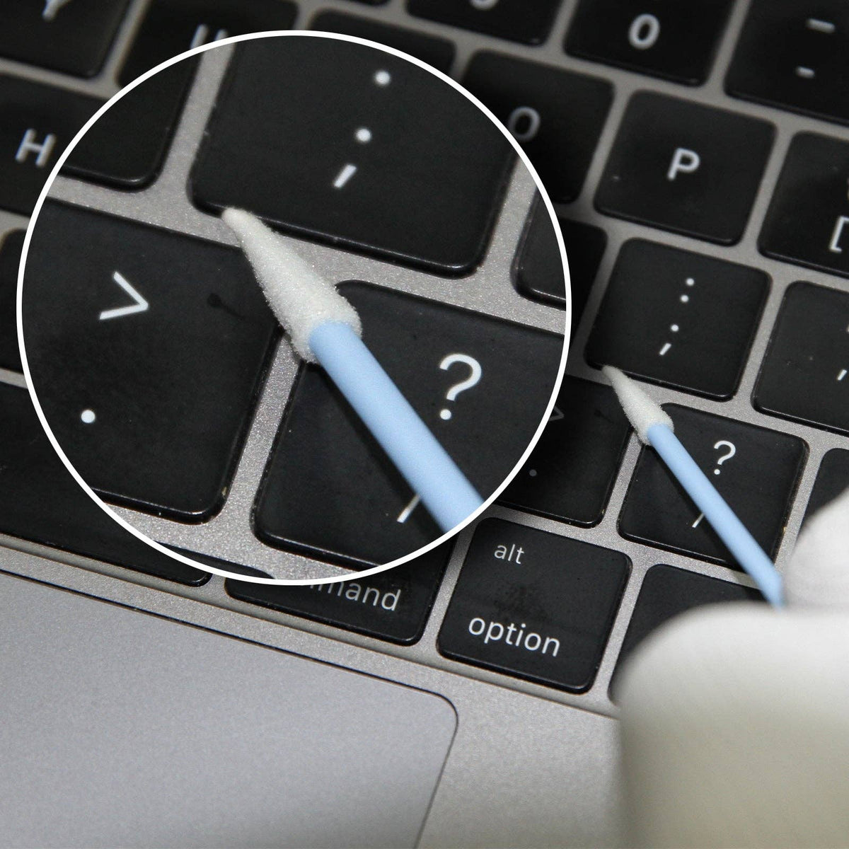 Close-up of a laptop keyboard with a stylus on the question mark key.