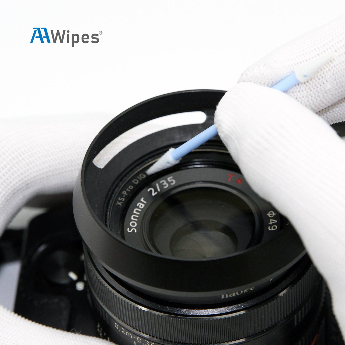 A close-up of a camera lens being cleaned with a blue-handled cotton swab by a gloved hand. The AAWipes brand logo is visible in the top left corner.