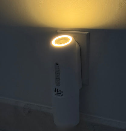 White diffuser with night light plugged into a wall socket with a warm glow.