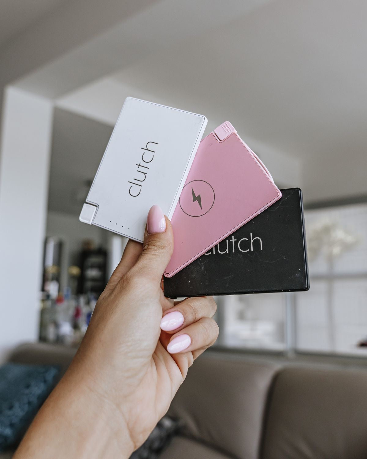 Hand holding a white, pink, and black Clutch Pro. 