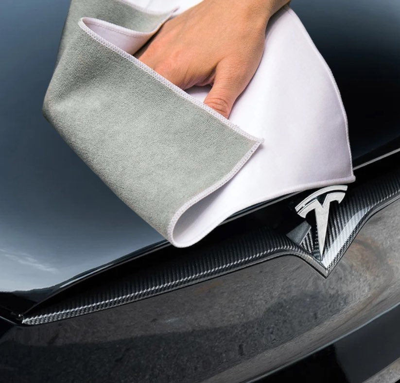 Large white and grey multipurpose microfiber cloth wiping the hood of a Tesla.