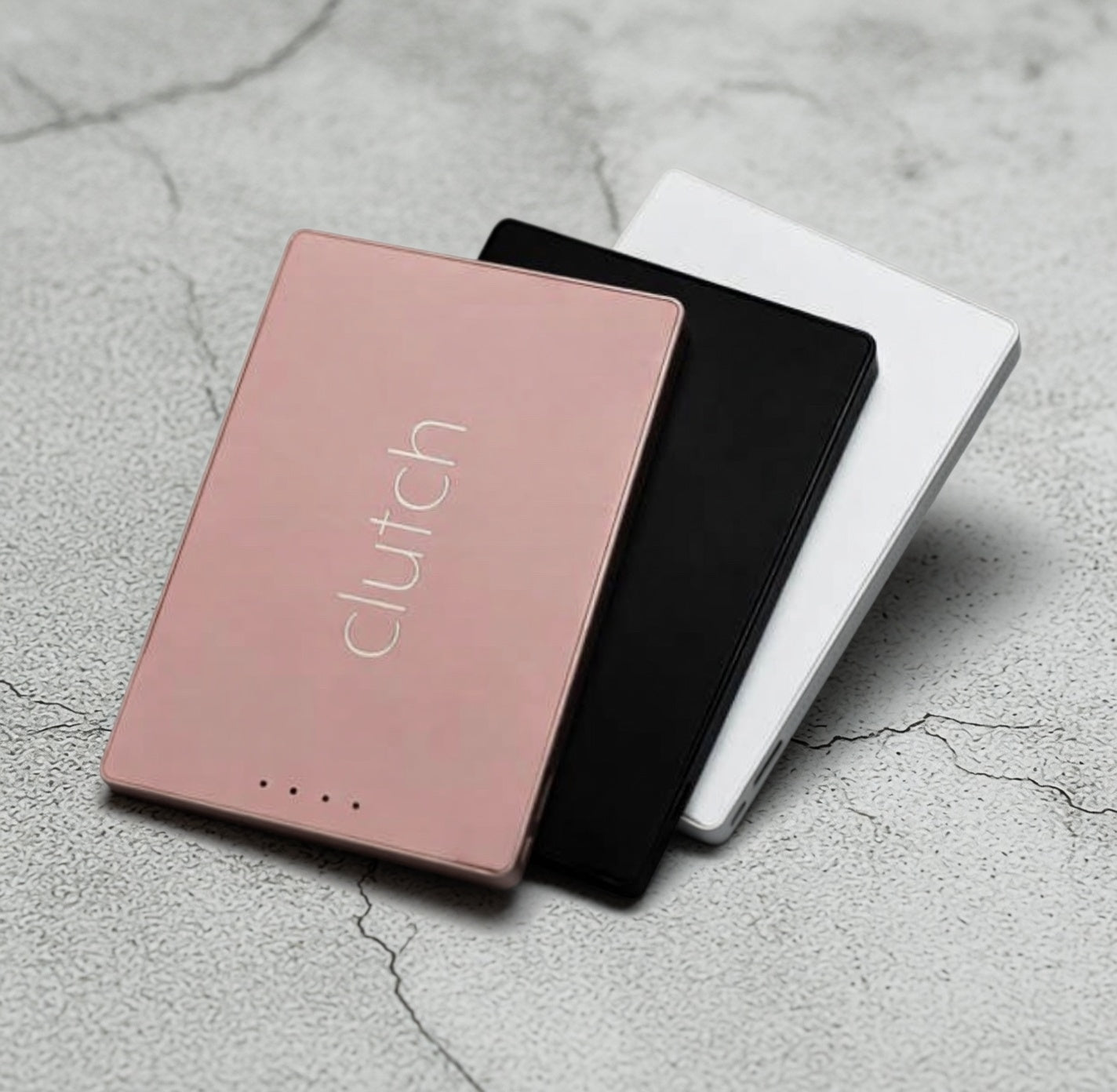 Three clutch chargers in pink, black, and white on a textured gray surface.