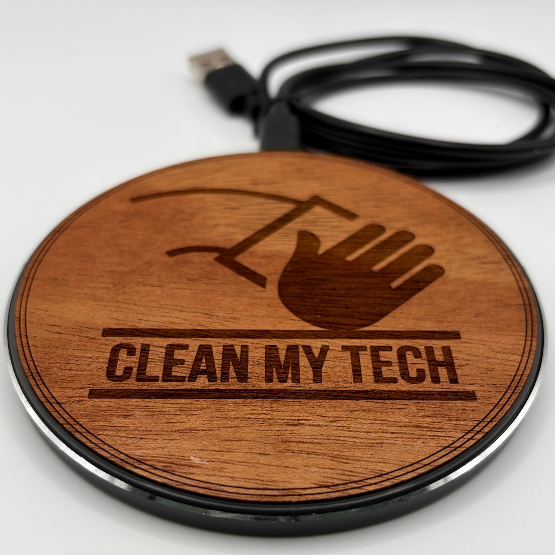 Wooden round charger with 'Clean My Tech' engraving and USB cable on a white background