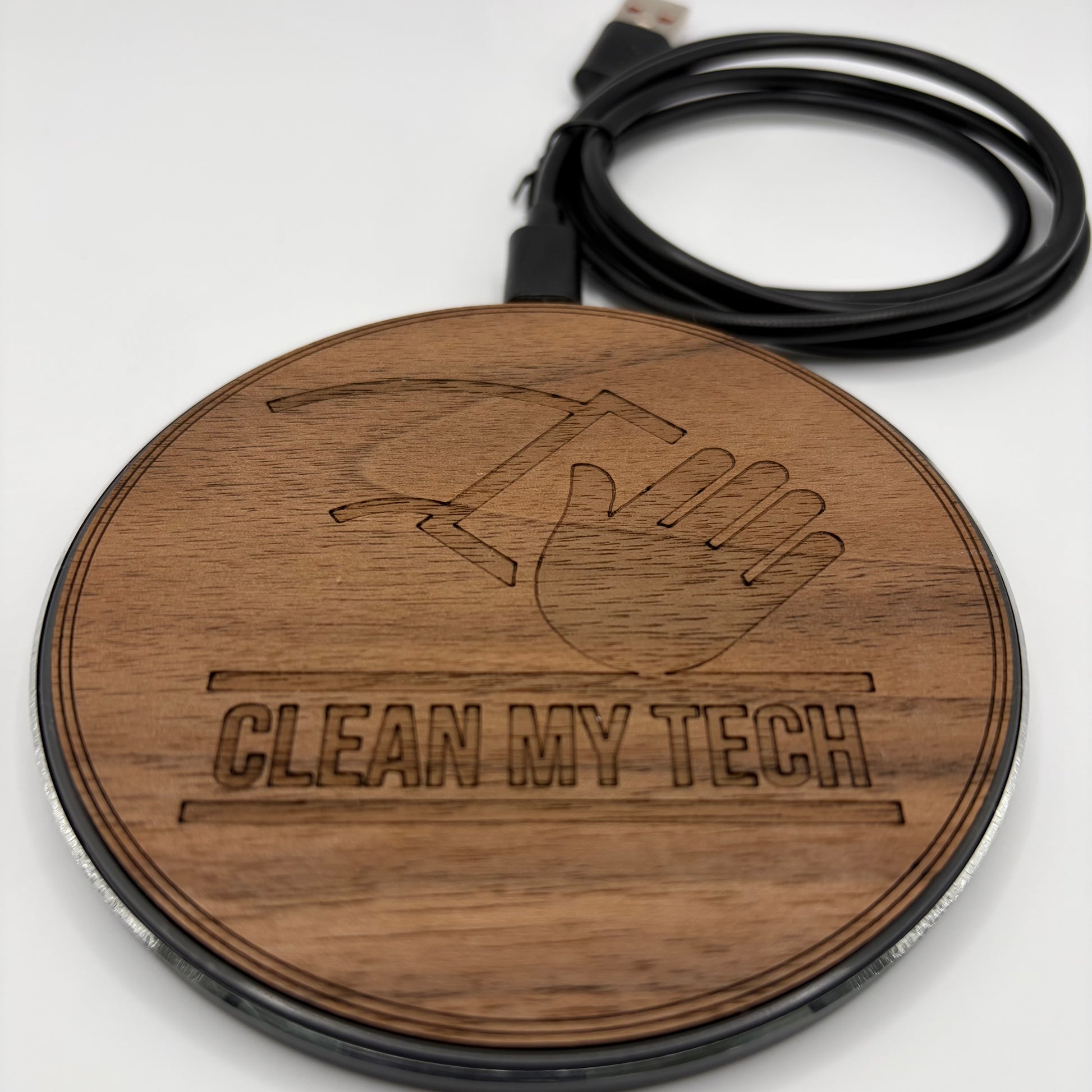 Wooden round charger with 'Clean My Tech' engraving and USB cable on a white background
