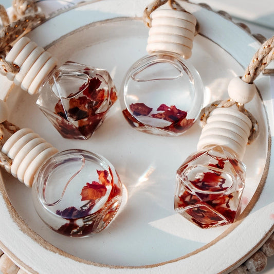 Four small glass bottles with dried flowers on a decorative stand, accompanied by a 'Love Spell' label.