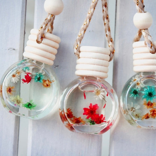 Three hanging glass bulbs with dried flowers on a light wooden background