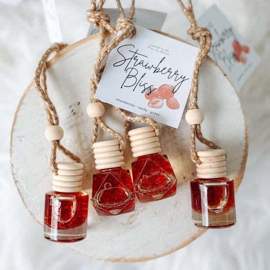 Set of small bottles with red liquid on a decorative stand, labeled 'Strawberry Bliss'.
