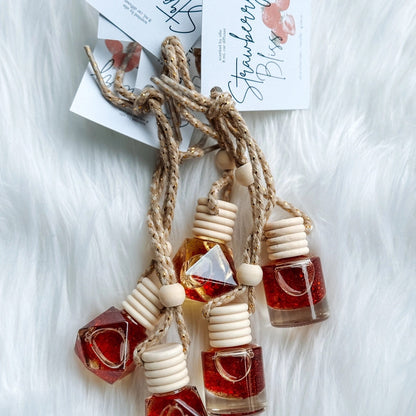Set of small bottles with wooden caps on a white fluffy surface, with 'Strawberry Bliss' card in the background.