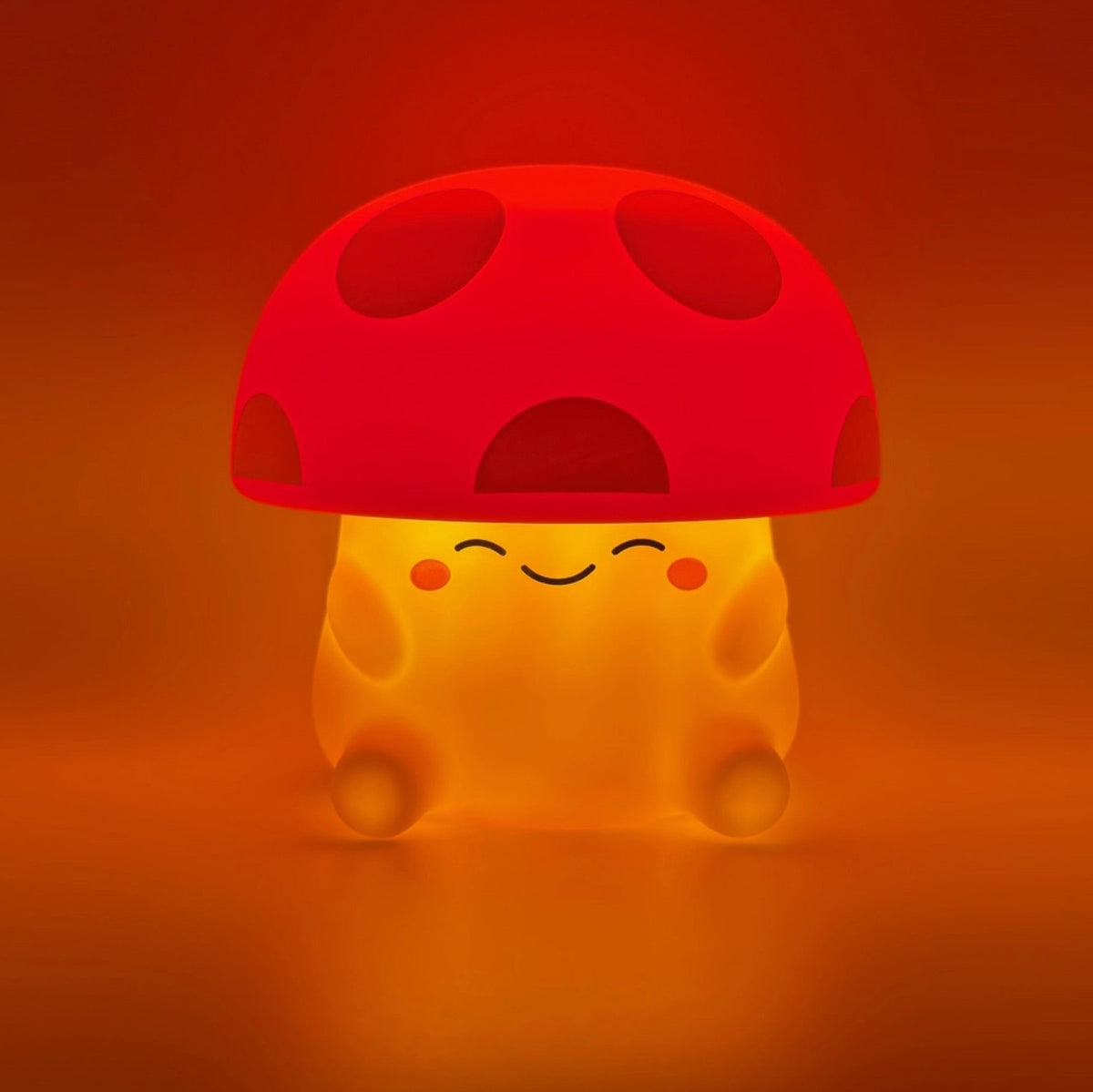 A cute mushroom-shaped glowing night light with a red cap and a warm yellow-orange body, shown against a glowing orange-red background.
