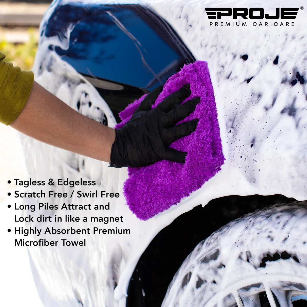 A person wearing a black glove washes a white foamy car with a bright purple microfiber towel. The Proje Premium Car Care logo is visible in the top right, and product feature text is shown on the left.