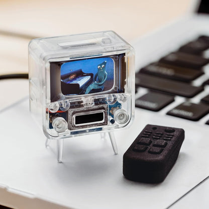 Small transparent electronic device with a screen on a desk next to a keyboard