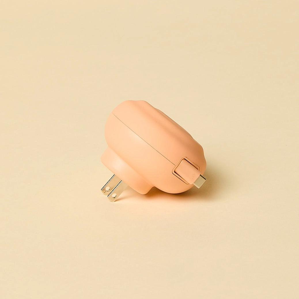 Round peach-colored retractable charger on a beige background