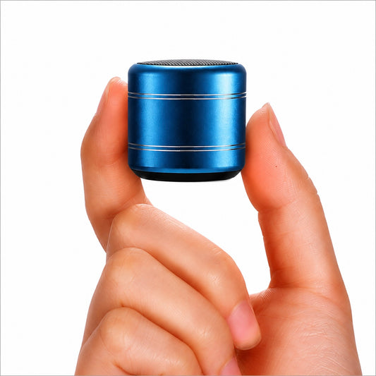 A small cylindrical blue portable speaker with silver metallic rings, held between two fingers to show its compact size against a plain white background.