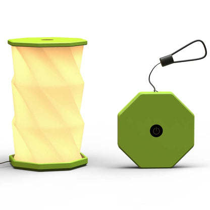 A lime portable folding lamp  shown on a clean white background. The lamp is unfolded and illuminated with a geometric, faceted design in warm yellow.