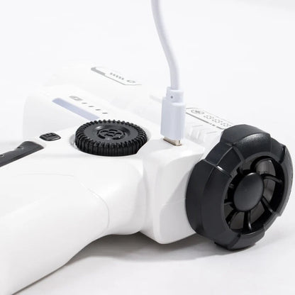 A close-up of a white handheld electronic device with black circular dials and a white charging cable plugged into it, photographed on a clean white background.