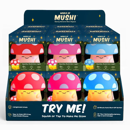 A retail display box of six MUSHI squishy mushroom lights in different colors: red, pink, blue, yellow, purple, and orange. The display box is dark blue with 'WORLD OF MUSHI' and 'TRY ME!' printed on it.