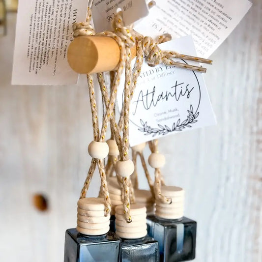 Black Atlantis bottles with wooden caps and hanging product tags displayed on a wooden peg rack.