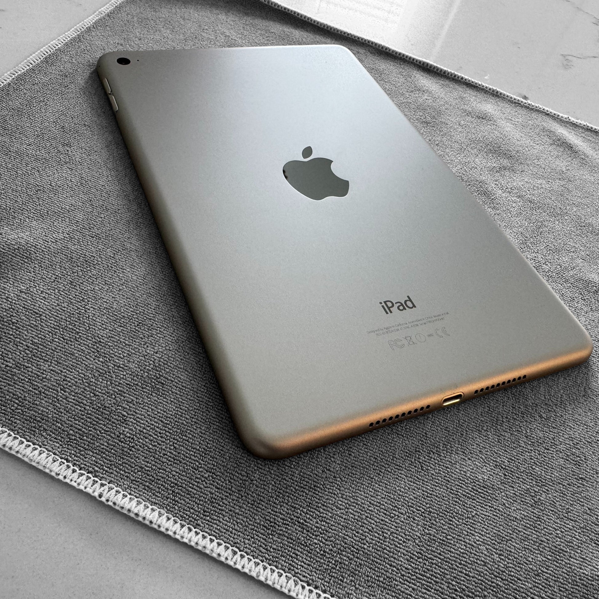 iPad mini laying face down on a large grey multipurpose microfiber cloth.