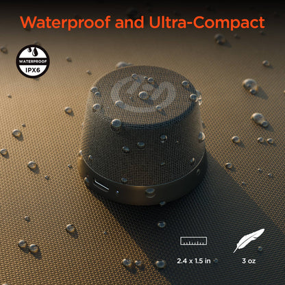 Black portable speaker on a textured surface with water droplets, highlighting waterproof feature.