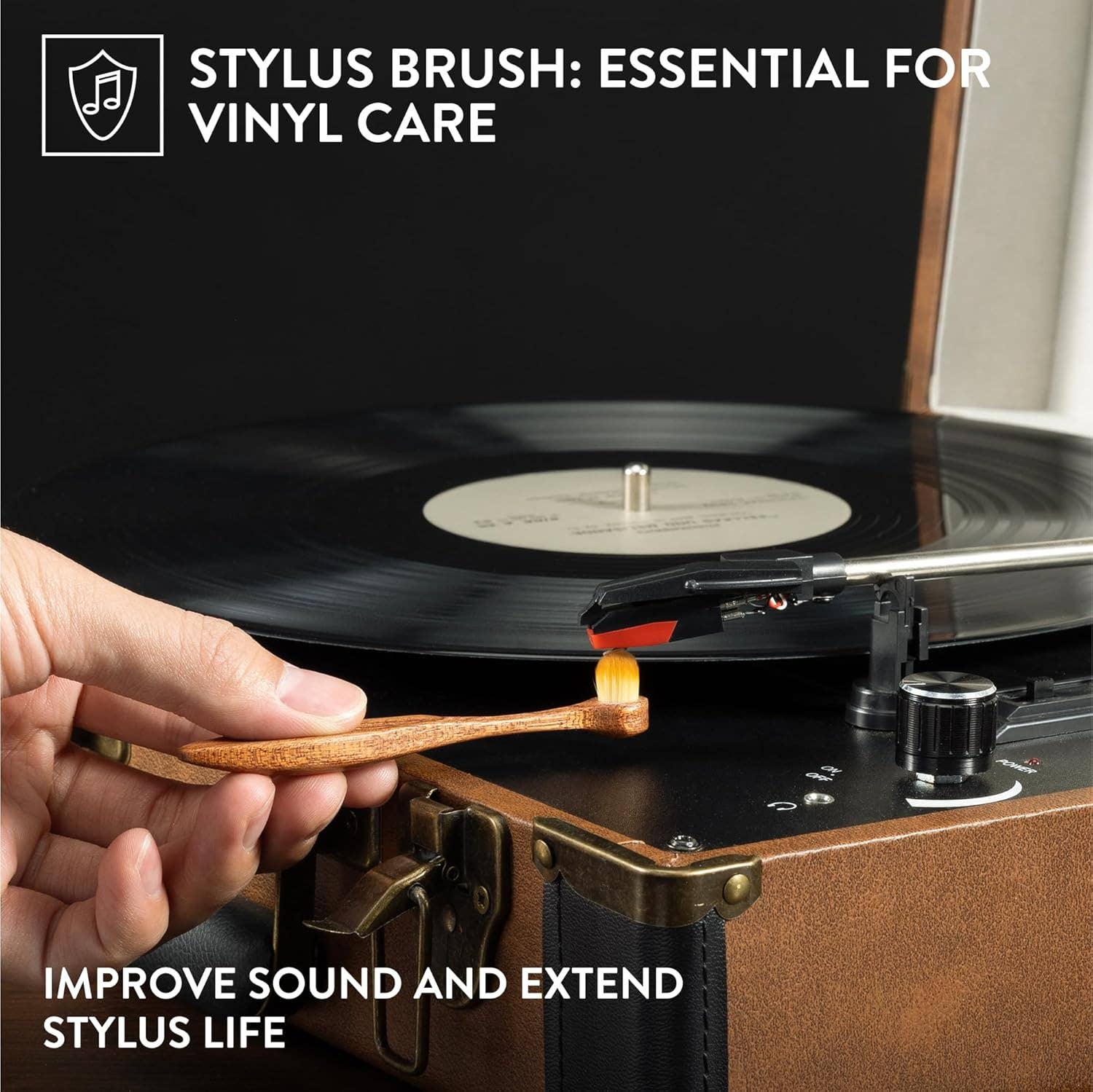 A hand holds a small wooden stylus brush near a turntable needle, with text reading 'STYLUS BRUSH: ESSENTIAL FOR VINYL CARE' and 'IMPROVE SOUND AND EXTEND STYLUS LIFE'.