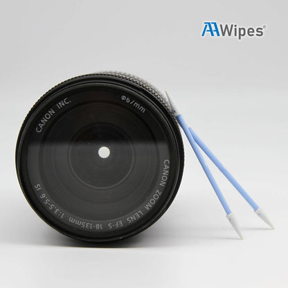 A Canon zoom lens shown on a light gray background with two blue and white cleaning wipes from AA Wipes leaning against it. The Canon brand is clearly printed on the lens.