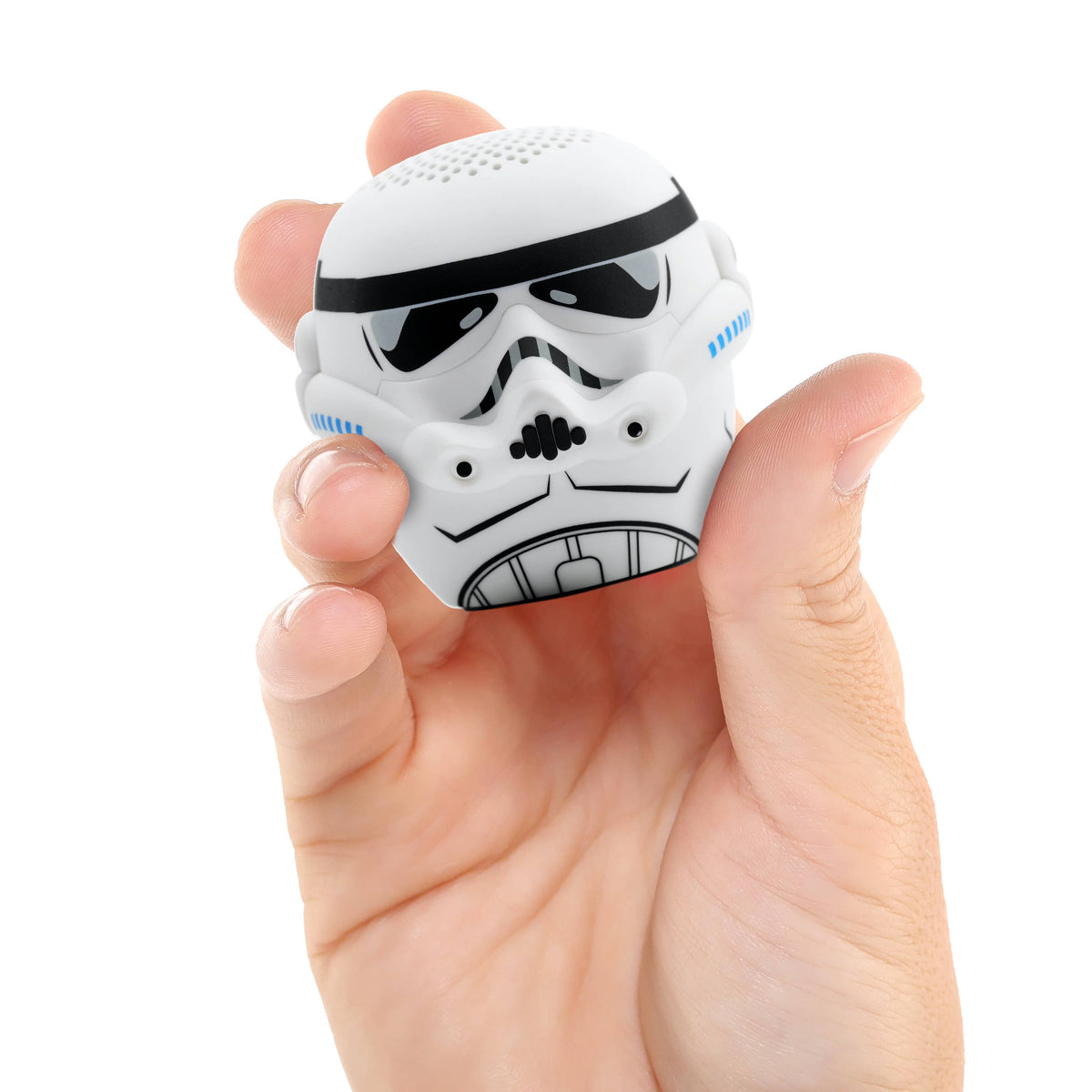 Small speaker shaped like a stormtrooper helmet held in a hand against a white background