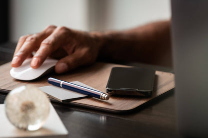WUDN large real wood wireless charging mouse pad with built-in 15W Qi fast charger, shown in use with a man using a mouse while his phone charges.