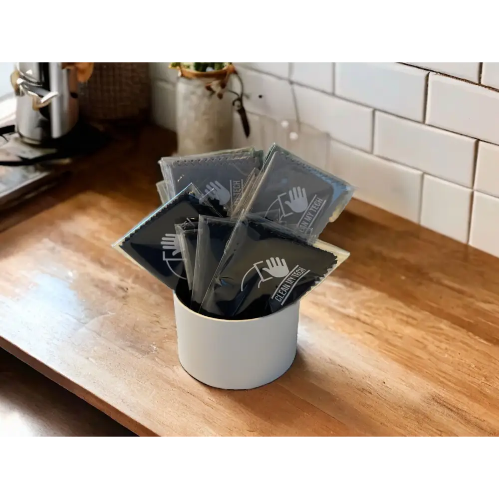 Black ’clean with these’ microfiber cloth packets in clear plastic packaging, neatly arranged in a white cylindrical container.
