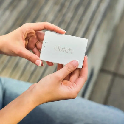 White rectangular clutch portable charger with subtle gray branding and four small indicator lights along the top edge.