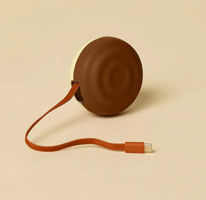 Counterpart usb-c retractable charger is a brown and cream circular portable wall charger with leather strap and usb-c cord