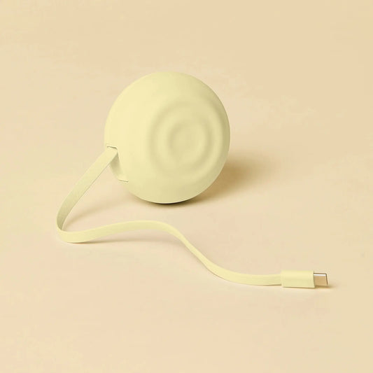 A soft, pale green circular portable charger with a smooth matte finish and concentric ridges on its surface.