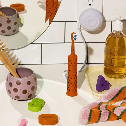 Orange polka-dotted electric toothbrush with blue and white bristles