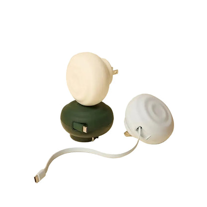 Two compact, round portable chargers with a matte finish—one in dark green and one in off-white—each featuring an integrated plug and usb-c cable.